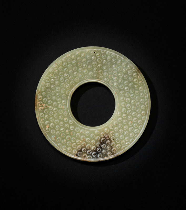A pale celadon and russet jade 'comma scrolls' disc, bi, China, Warring ...