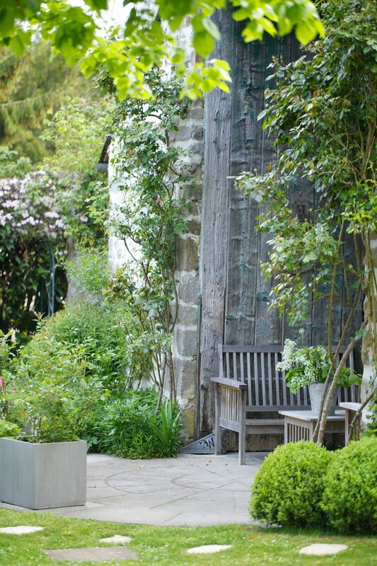 French farmhouse exterior with bench, boxwood, and lush greenery via Grange de Charme. #frenchfarmhouse #patio #garden #stonecottage