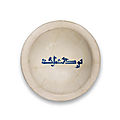 A signed abbasid slip-painted calligraphic pottery bowl, mesopotamia, 9th century